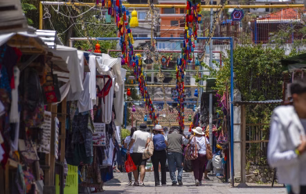 Visitantes caminando entre puestos de artesanías y tejidos típicos en un mercado de Guatemala