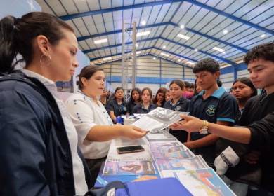 Estudiantes de uniforme reciben información sobre becas de una representante durante la Feria Nacional de Becas 2026 en Guatemala