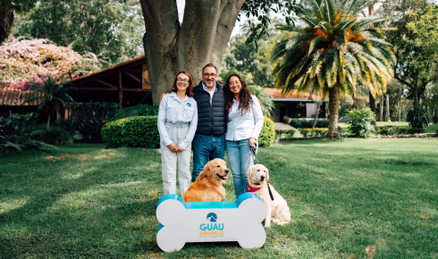 "Equipo de Guau Señoriales: tres personas junto a dos Golden Retriever en jardín con logotipo en forma de hueso, servicio de acompañamiento emocional para familias en duelo en Guatemala"